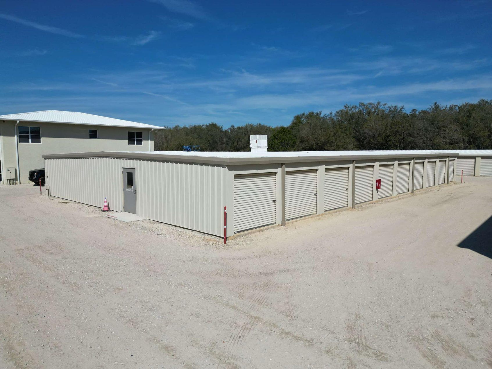 Rows of clean drive-up storage units with roll-up doors under a blue Florida sky